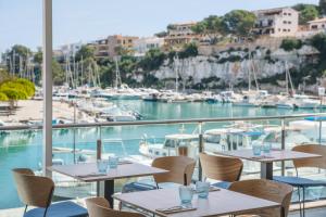 a restaurant with tables and chairs and a marina at Porto Drach Aparthotel & Suites in Porto Cristo