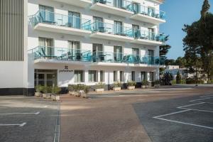 an empty parking lot in front of a white building at Porto Drach Aparthotel & Suites in Porto Cristo