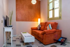 een woonkamer met een oranje bank en een tafel bij DescubreHome Macarena Town Center in Sevilla