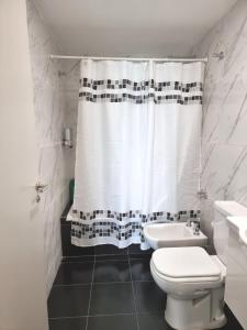 y baño con aseo y cortina de ducha. en Monoambiente San Martin en San Salvador de Jujuy