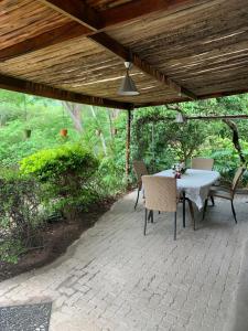 a patio with a table and chairs under a wooden roof at Nightjar Guest Lodge in Nelspruit