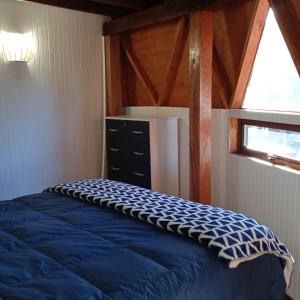 Un dormitorio con una cama azul y una ventana en Domo Las araucarias, en Negrete
