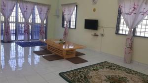 een kamer met een houten tafel in een kamer met ramen bij Room/Homestay NazaDja in Sungai Besar