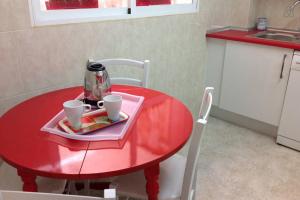 Una mesa roja con dos tazas encima. en Cason del Corpus, en Toledo