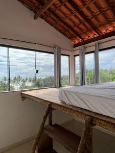 a bedroom with a bed and large windows at Hostel Pipe House in Ilhéus