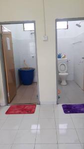 a bathroom with a toilet and a tub and a bathroom with rugs at Room/Homestay NazaDja in Sungai Besar