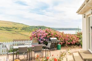 a patio with a bbq grill and flowers at Lower Upover - Woolacombe-4 Bed-Sleeps 7-TJSLUO in Woolacombe