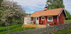uma casa vermelha e branca com um deque de madeira em Snokebo Gård em Vimmerby