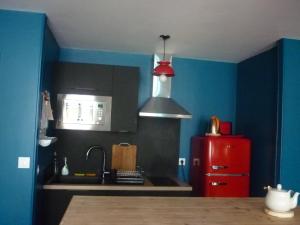 La cuisine est équipée d'un réfrigérateur rouge et d'un évier. dans l'établissement Nénuphar, à Autun