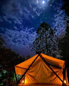 una tienda naranja se ilumina por la noche en El Paraje Camping, en Piribebuy