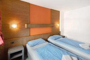2 łóżka w małym pokoju z pomarańczowymi ścianami w obiekcie Casa San Marco n 7 w Livigno