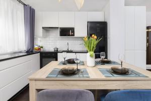 a kitchen with a table with glasses and flowers on it at Warsaw Cosy&Sunny Apartment Górnośląska by Renters in Warsaw