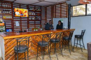 two people sitting at a bar in a room at Naivasha Peppercorn Holiday Resort in Naivasha