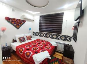 a bedroom with a red bed and a red blanket at Khiva Tosh Darvoza in Khiva