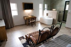 a bathroom with a tub and a table and a sink at Villa Gracia Guesthouse in Klerksdorp