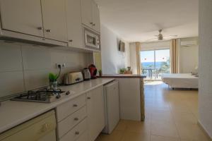 a kitchen with white cabinets and a view of the ocean at Deauville Miami platja in Miami Platja +45 photos