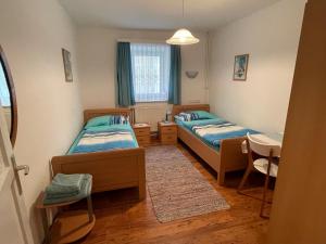 Kleines Zimmer mit 2 Betten und einem Tisch in der Unterkunft Gertis Blumenhof Privatzimmer, Ferienwohnung in Gmünd