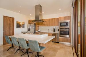 a kitchen with a white counter and chairs in it at Aromo Townhouse with private pool Reserva Conchal in Playa Conchal