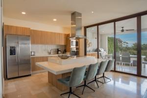 a kitchen with a island with chairs and a counter top at Aromo Townhouse with private pool Reserva Conchal in Playa Conchal