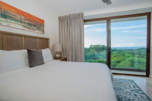 1 dormitorio con cama grande y ventana grande en Aromo Townhouse with private pool Reserva Conchal, en Playa Conchal