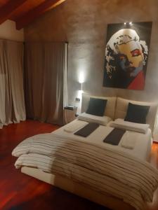 Il giardino di Pietro في مونزا: غرفة نوم مع سرير أبيض كبير مع لوحة على الحائط