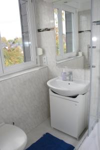 Baño blanco con lavabo y aseo en Helles Apartment in Berlin-Mariendorf, en Berlín