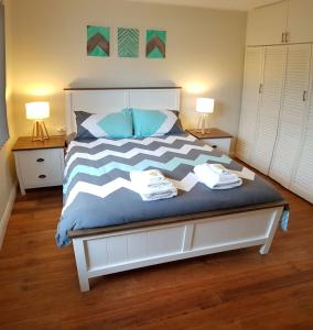 1 dormitorio con 1 cama de color azul y blanco en Baltica Beach House, en Culburra Beach