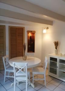 Aux Vieilles Murailles • Charmante maison & cour في مورليه: غرفة طعام مع طاولة بيضاء وكراسي