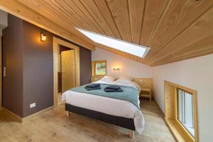 um quarto com uma cama grande e uma clarabóia em Chalet L'Urson, spacieux, jacuzzi, hammam et sauna em Gérardmer