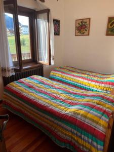 ein Schlafzimmer mit einem farbenfrohen Bett und einem Fenster in der Unterkunft Condominio Dorf in Sappada