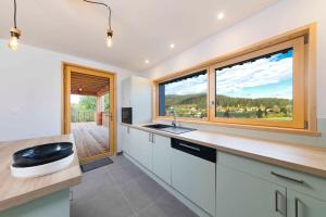 uma cozinha com um lavatório e uma grande janela em Chalet L'Urson, spacieux, jacuzzi, hammam et sauna em Gérardmer