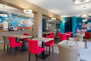 a restaurant with tables and chairs and a ferris wheel at B&B HOTEL Marne-la-Vallée Chelles in Chelles