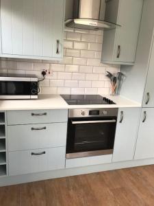 a kitchen with white cabinets and a stove top oven at The Lodge - Dog Friendly Farm Cottage in Norwich