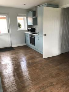 a kitchen with white walls and a wooden floor at The Lodge - Dog Friendly Farm Cottage in Norwich