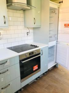 a kitchen with a stove and an open refrigerator at The Lodge - Dog Friendly Farm Cottage in Norwich