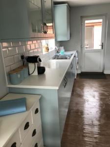 a white kitchen with a sink and a counter at The Lodge - Dog Friendly Farm Cottage in Norwich