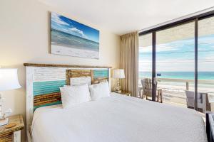 a bedroom with a bed and a view of the ocean at Surfside Resort in Destin