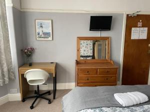 een slaapkamer met een bed, een bureau en een spiegel bij Maple Leaf Guest House in Bristol