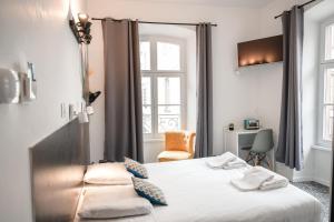 ein Schlafzimmer mit einem Bett mit einem Stuhl und einem Fenster in der Unterkunft Hotel des Arts - Centre Cathédrale in Straßburg
