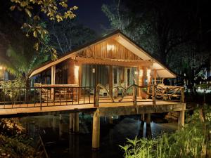 una pequeña casa en un puente de madera por la noche en วังภูไพร ฟาร์มสเตย์, en Wang Nam Khiao
