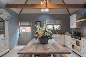 a kitchen with a wooden table with flowers on it at The Dairy by Bloom Stays in Ulcombe