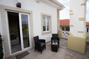 een patio met 2 zwarte stoelen en een balkon bij Casa Moiano in Oliveira do Hospital