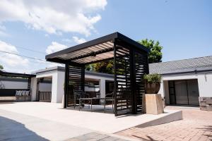 a black pergola with a table and chairs on a patio at Villa Gracia Guesthouse in Klerksdorp