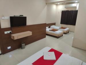 a room with two beds and a flat screen tv at Hotel Midtown Inn in Trimbak