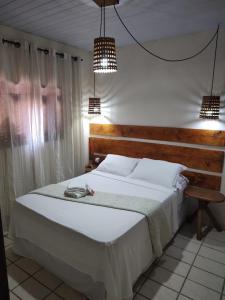 um quarto com uma grande cama branca e 2 luzes em Pousada Mar e Sol em Pipa
