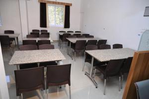 una stanza con tavoli e sedie in una classe di Hotel Mother Palace - Blue Rays a Baindūru