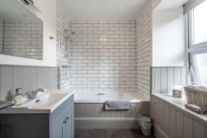 Baño blanco con bañera y lavamanos en Corriness House, en Poolewe