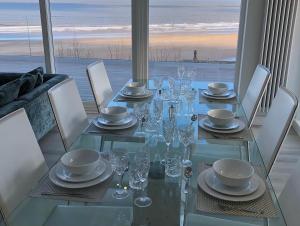 mesa de comedor de cristal con sillas y vistas al océano en Filey Beach House, en Filey