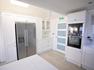 Una cocina con gabinetes blancos y un refrigerador. en Filey Beach House, en Filey
