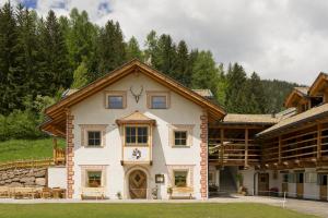 een groot wit huis met een dak bij Agritur el mas in Moena